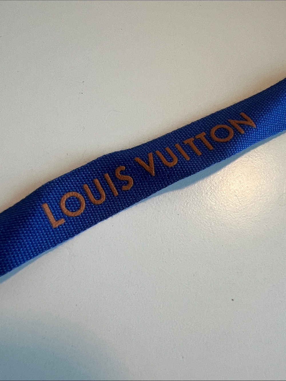 57 inches of blue Louis Vuitton ribbon with orange letters
